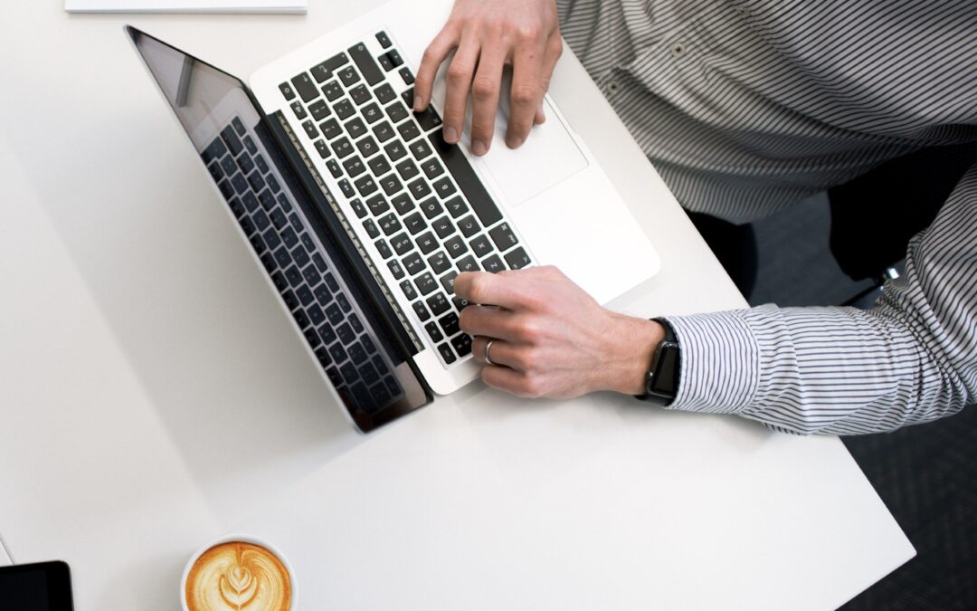 person typing on laptop next to coffee mug