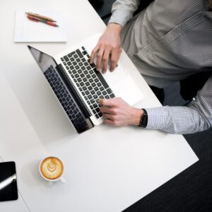 person typing on laptop next to coffee mug
